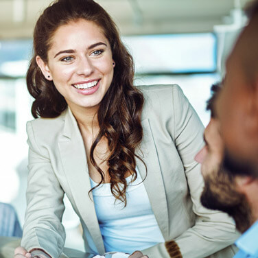 a woman in a suit jacket smiles at her coworkers